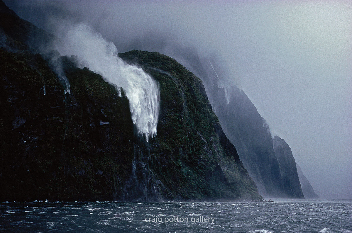 Par une journée de tempête, les eaux d’une cascade s’envolent vers les hauteurs d’un fjord.