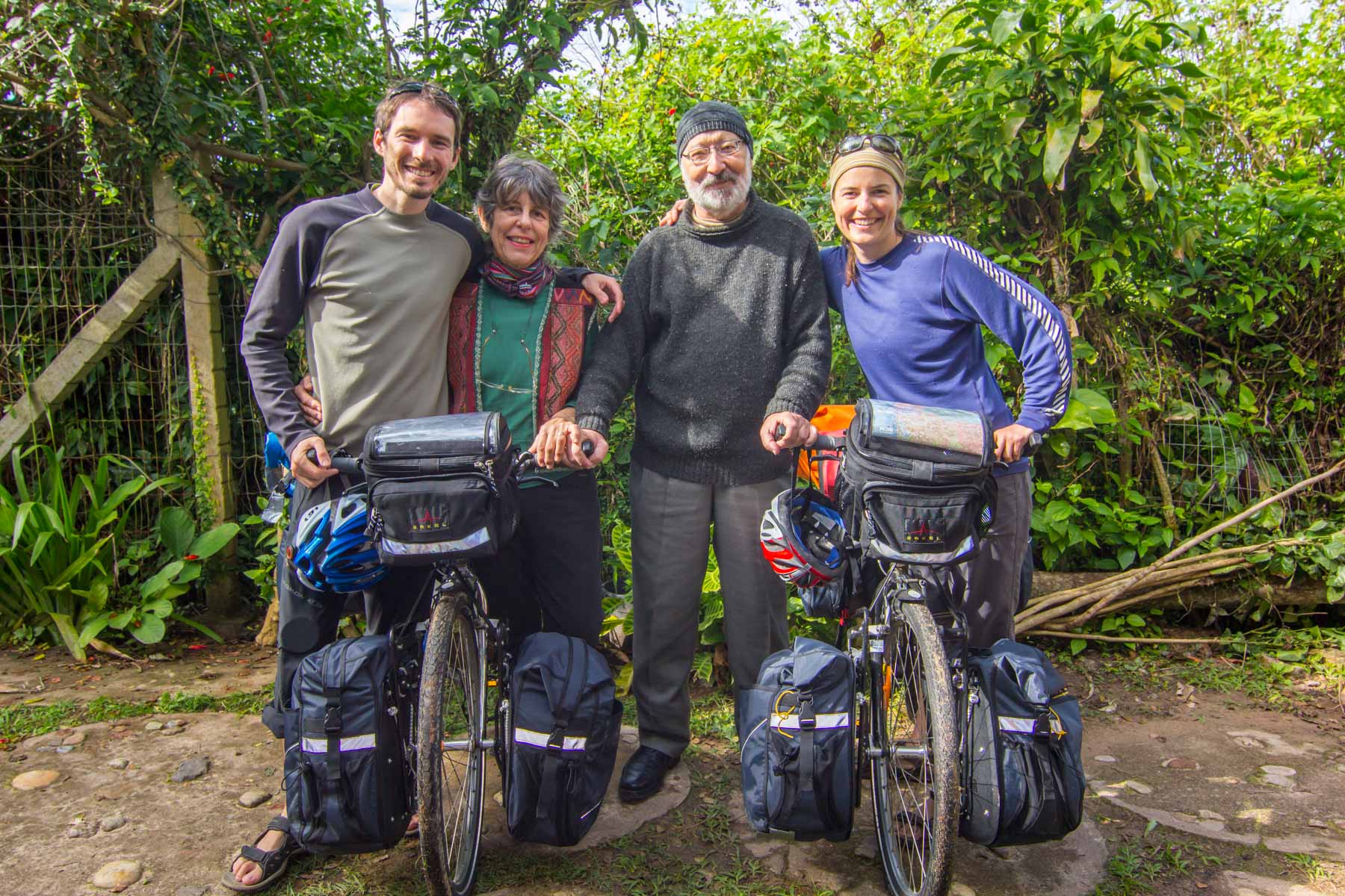 Près d’une nature luxuriante, un jeune homme et une jeune jeune posent pour la photo avec leurs vélos et un couple à la retraite.