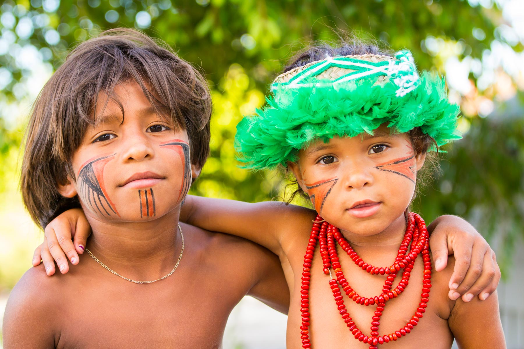 Portrait de deux enfants de la tribu Pataxós au Brésil avec des peintures traditionnelles rouge et noir sur les visages.