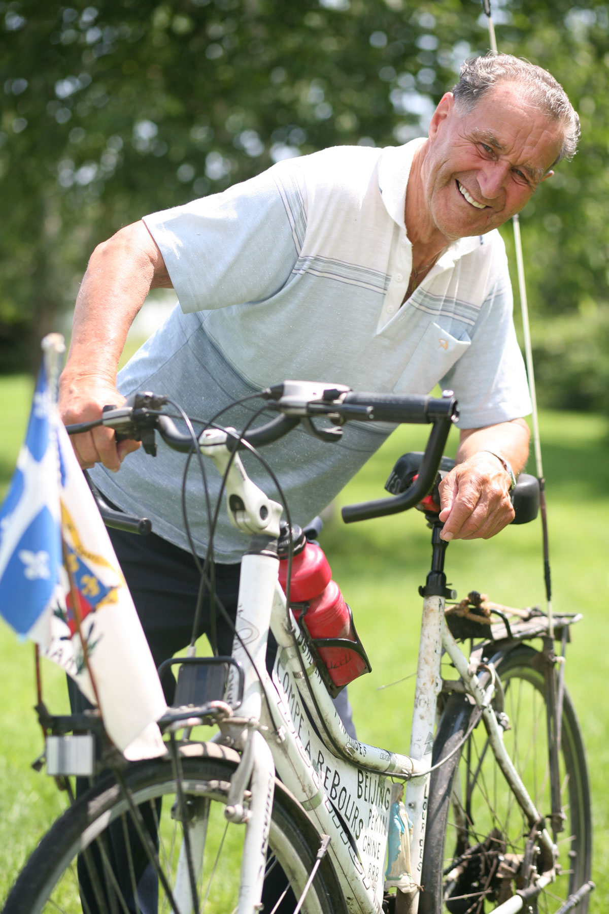 Un octogénaire pose fièrement avec son vélo blanc et sourit au photographe.