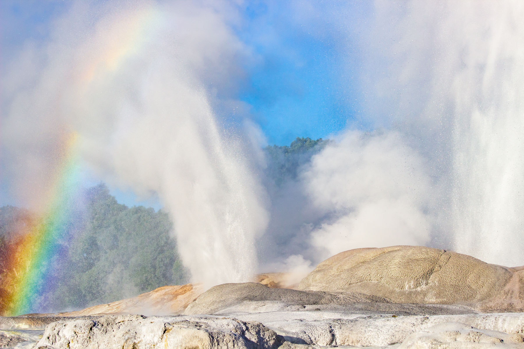 Apparition d’un arc-ciel durant l’éruption d’un geyser par une journée ensoleillée.