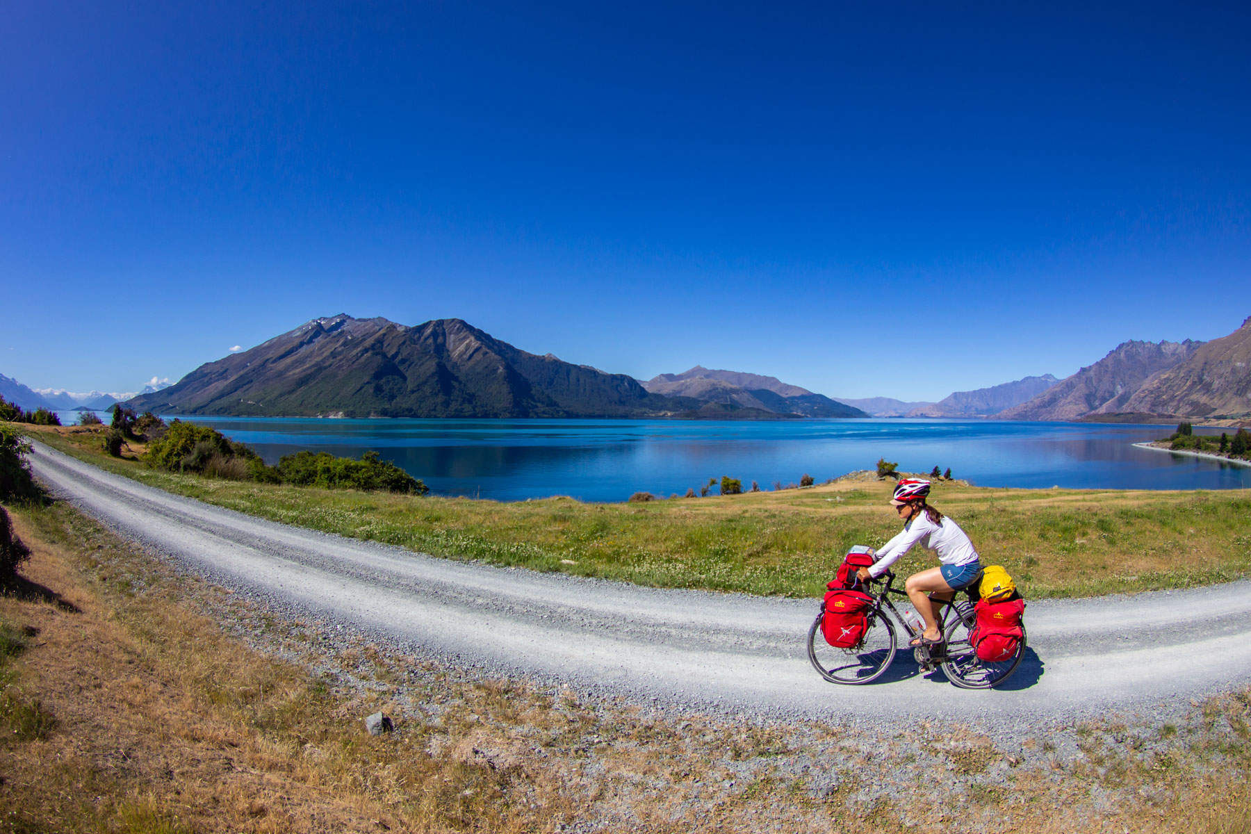 Une femme à vélo longe le troisième plus grand lac de Nouvelle-Zélande.