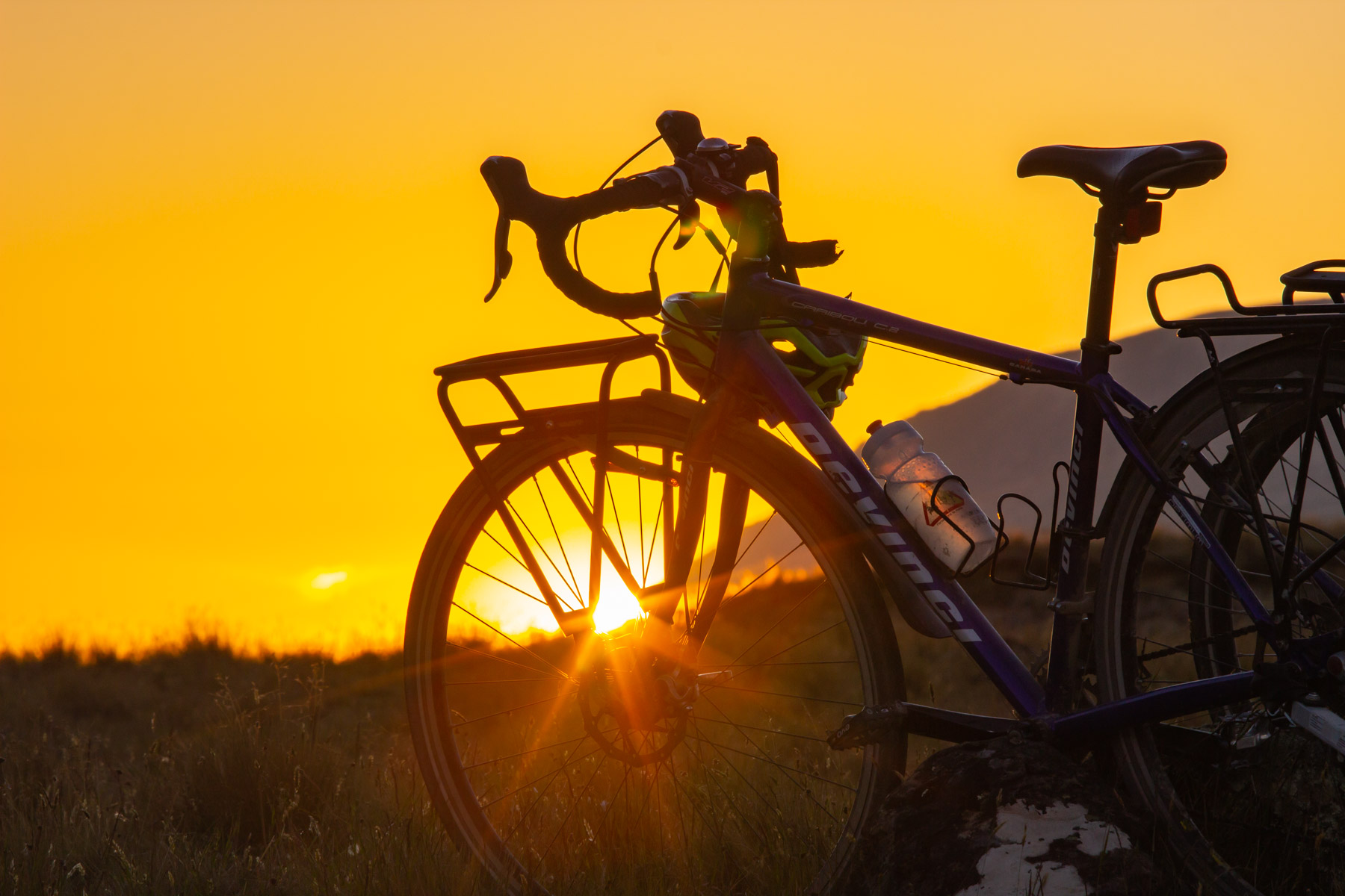 Silhouette d’un vélo de route devant le coucher du soleil.