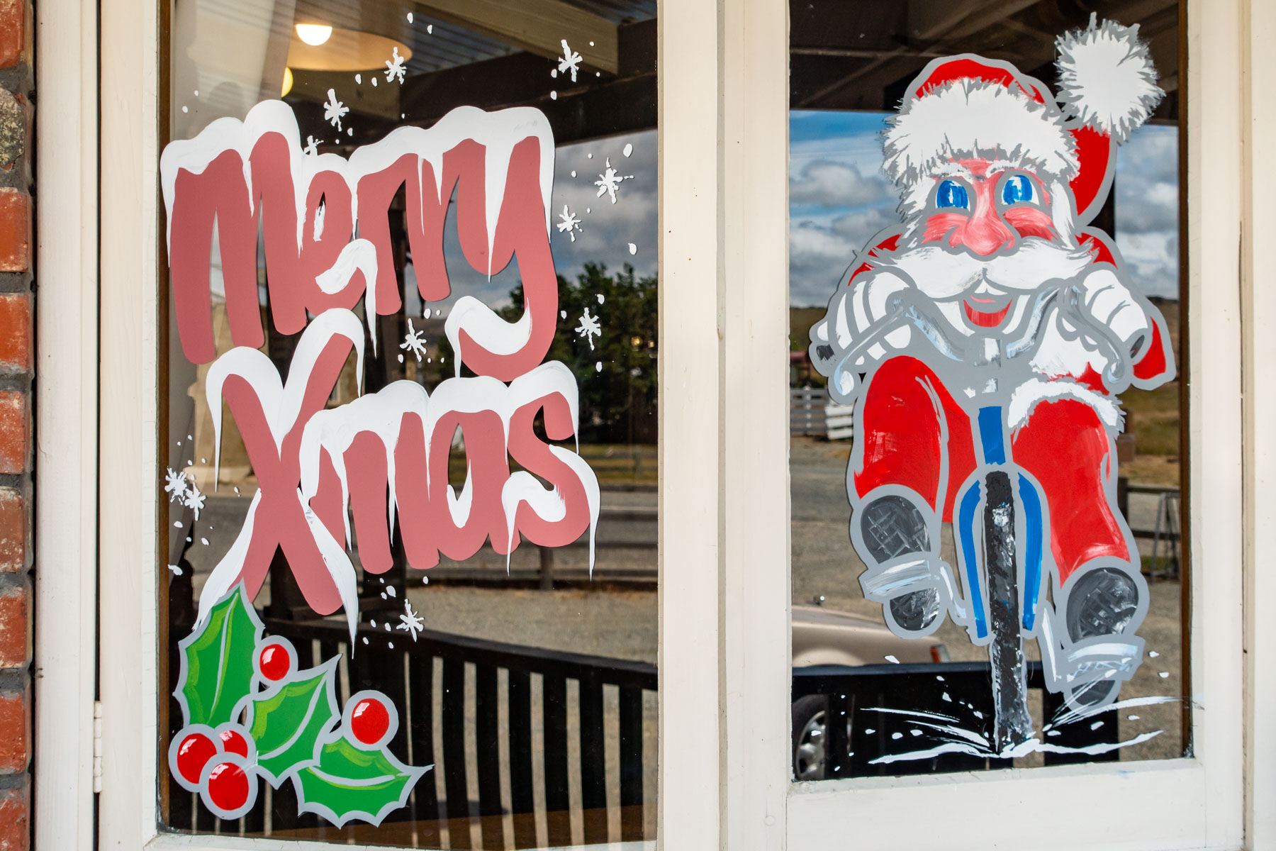Sur la vitre d’une fenêtre, dessin coloré du père Noël à vélo.