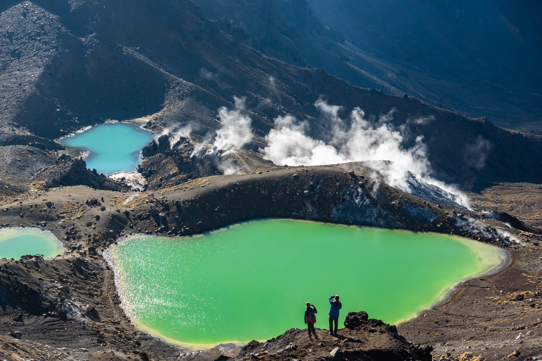 Vue sur trois petits lacs couleur émeraude nichés au creux des montagnes.