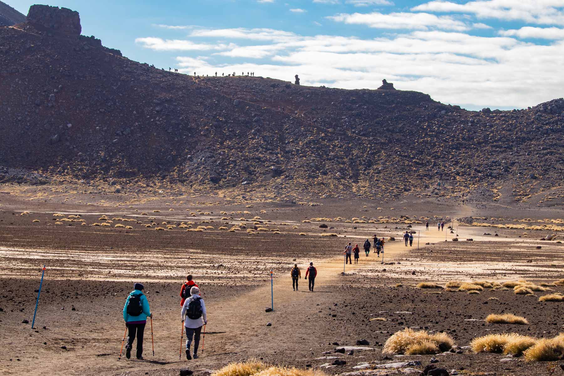 De petits groupes de randonneurs marchent sur un plateau rocailleux.